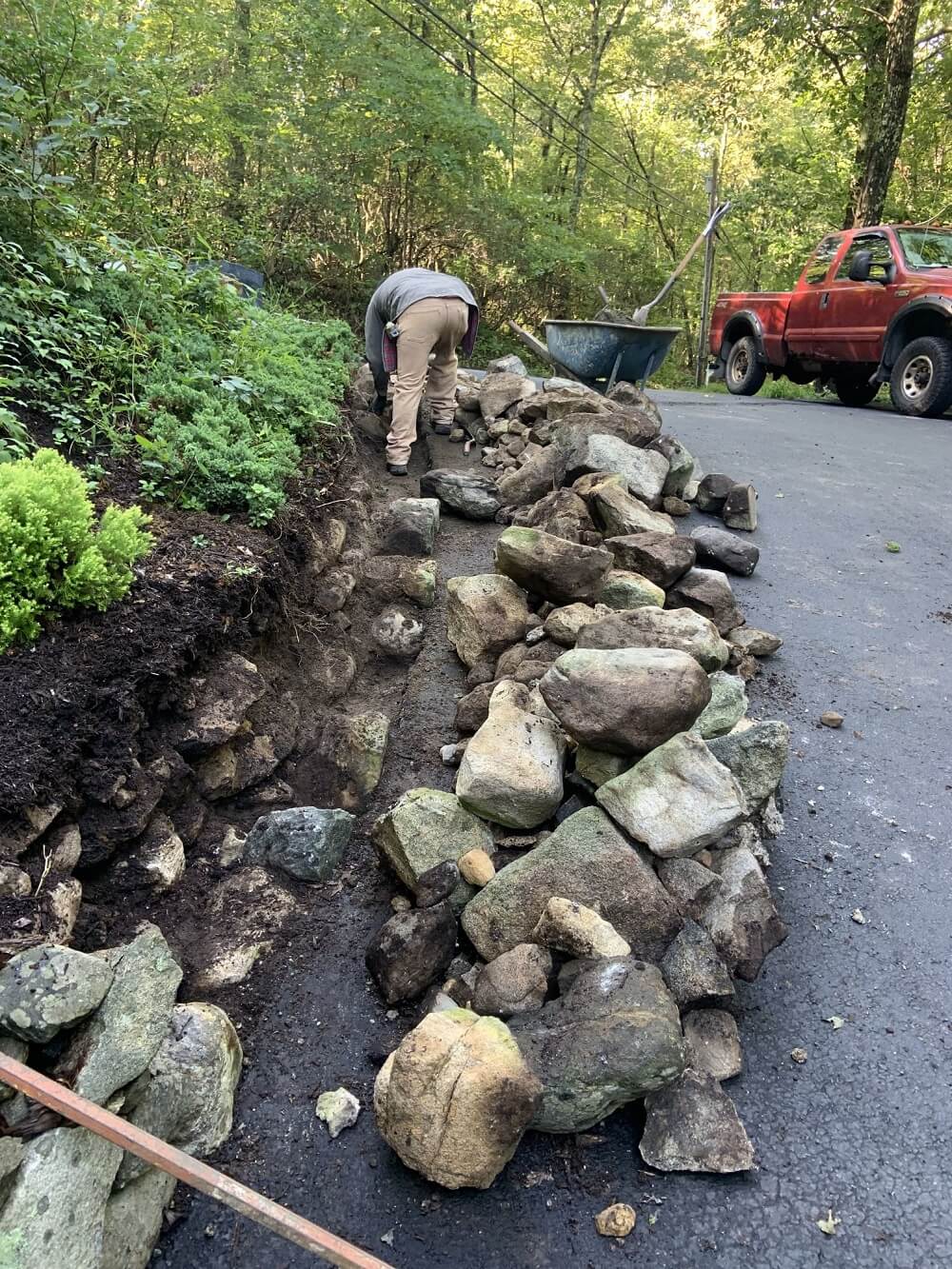 A man is building a rock wall in a scenic landscape.