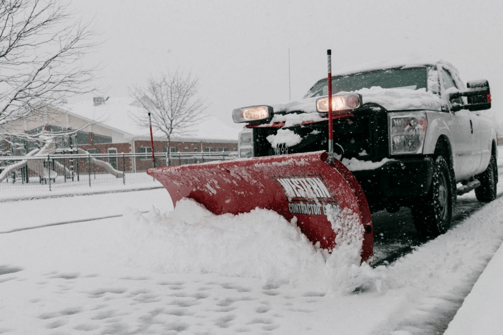 A snow plow truck providing snow plowing service on a street.